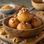 Greek honey donuts glazed with honey and walnuts in a rustic bowl